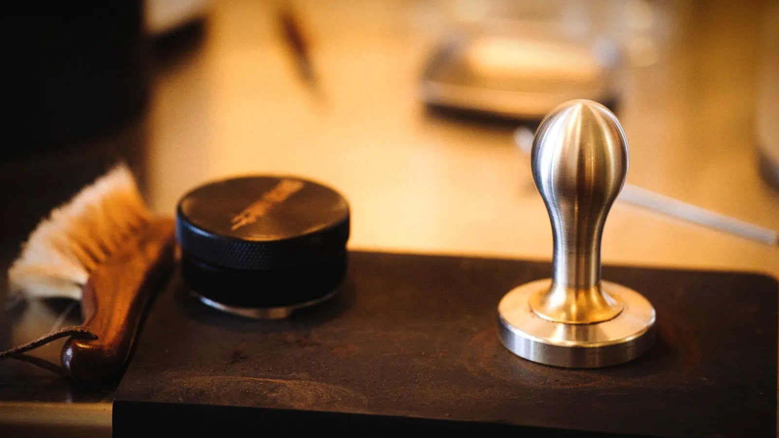 Bristle brush, distribution tool and tamper on a dark counter