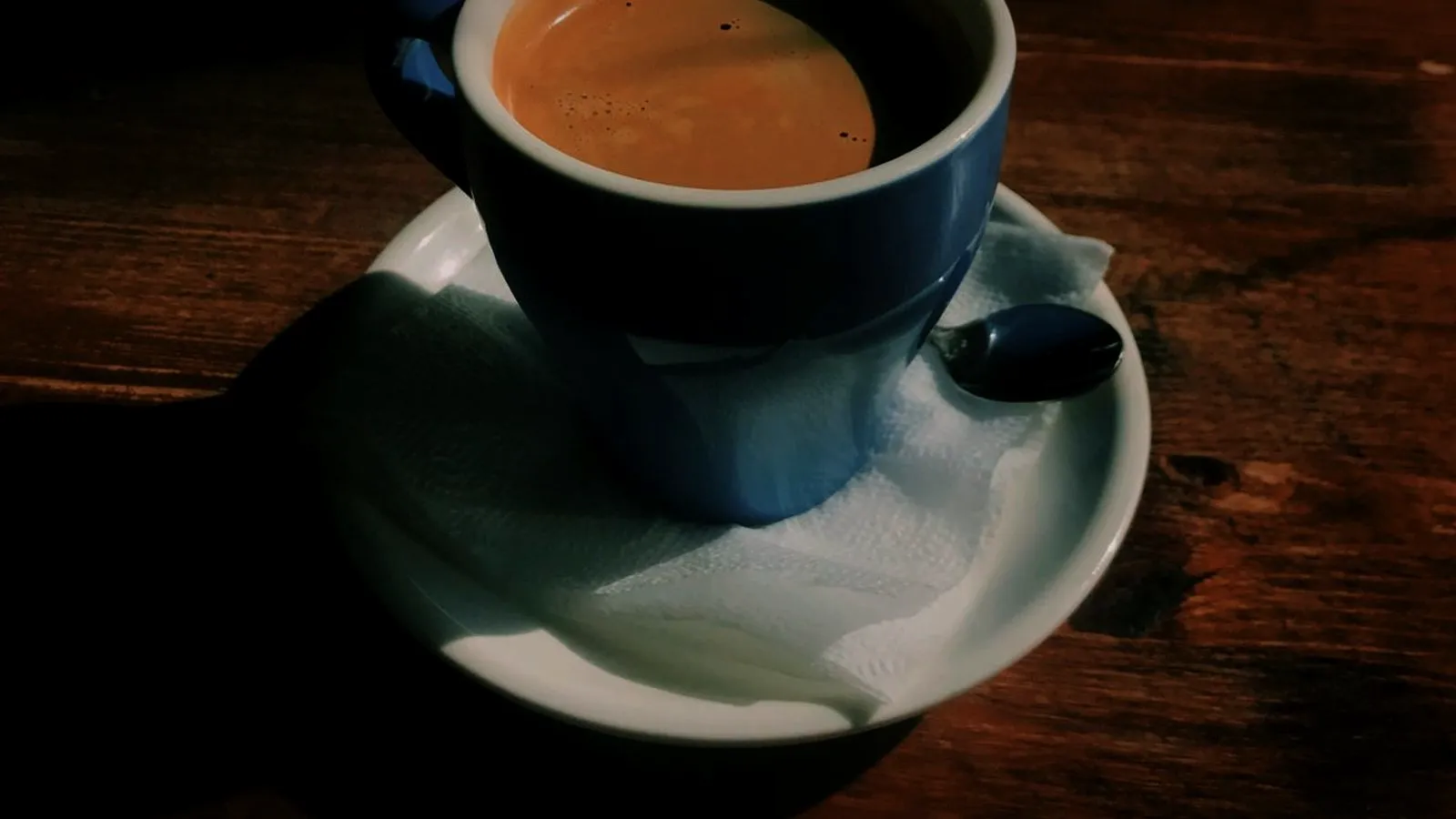 Freshly pulled espresso with crema in a dark blue cup on a saucer
