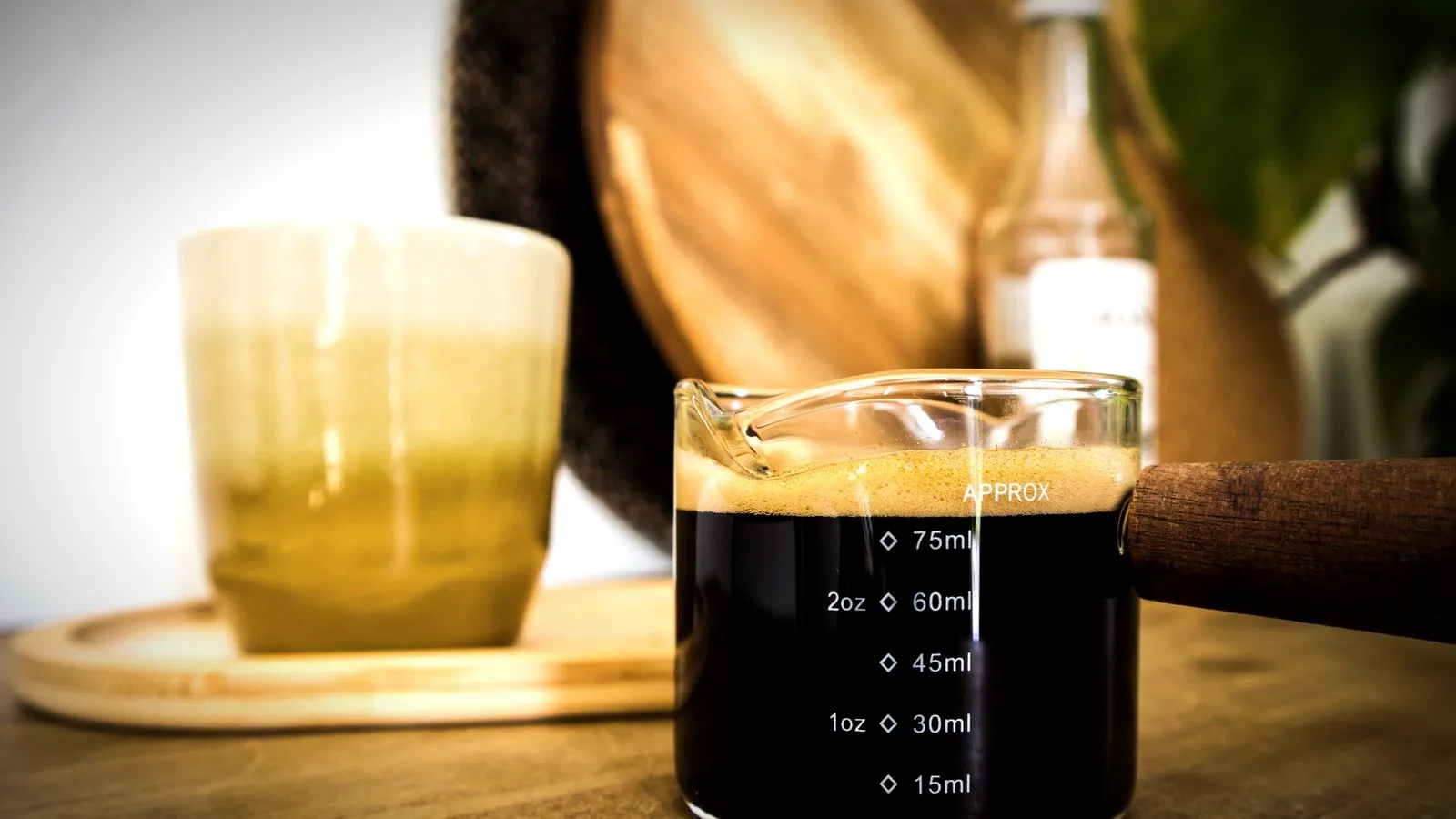 Espresso with a layer of crema in a small measuring glass marked in ounces and milliliters