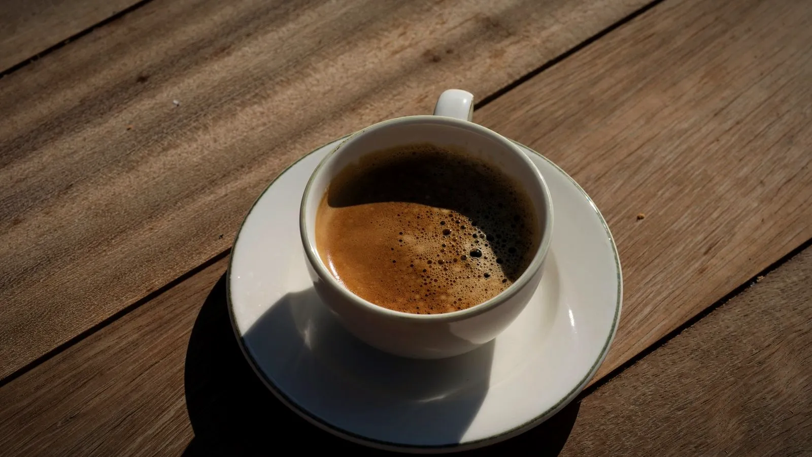 Espresso with a thin, patchy crema in a white cup on a wooden table