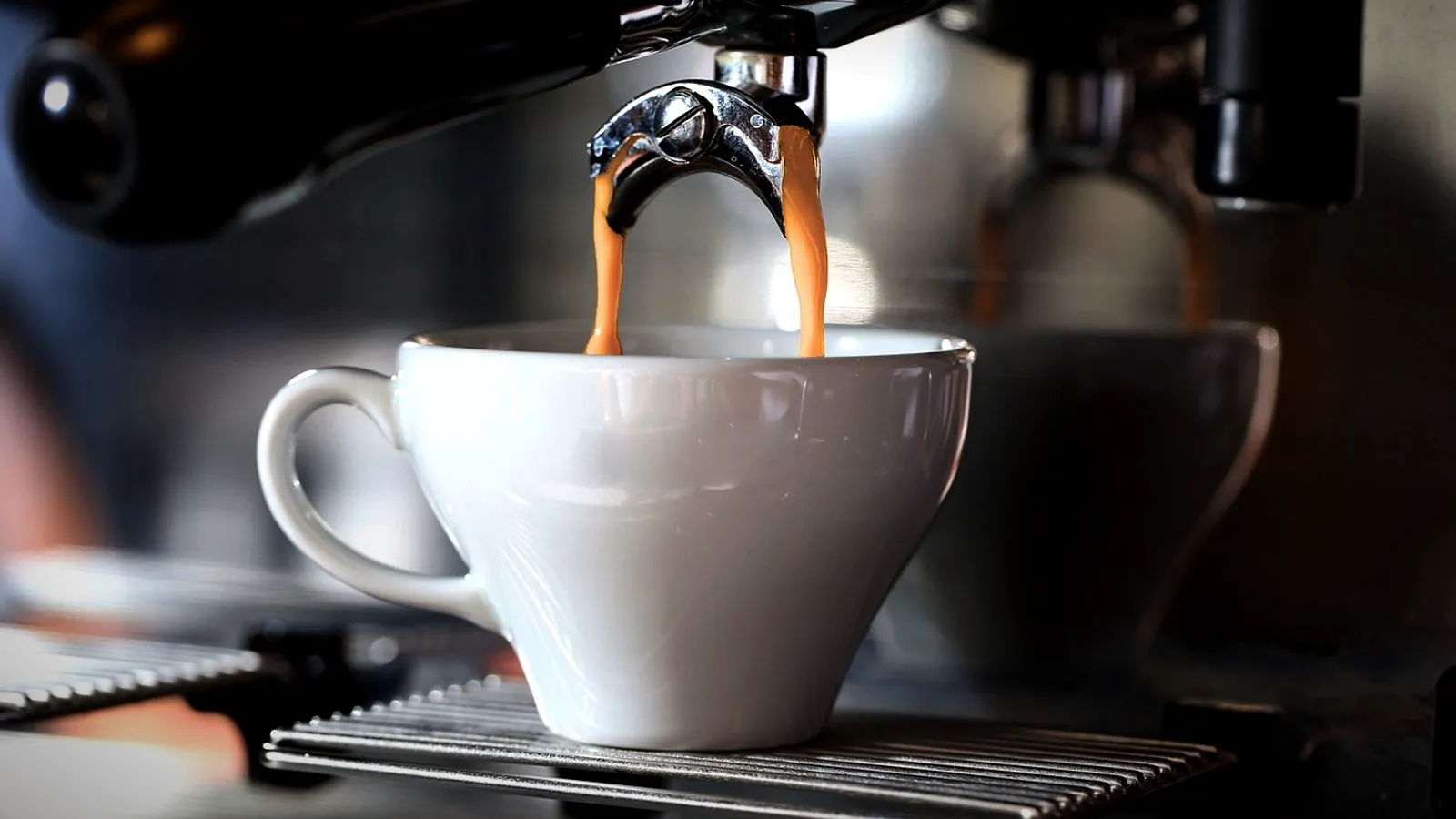 Espresso pouring from a machine into a thick white ceramic cup