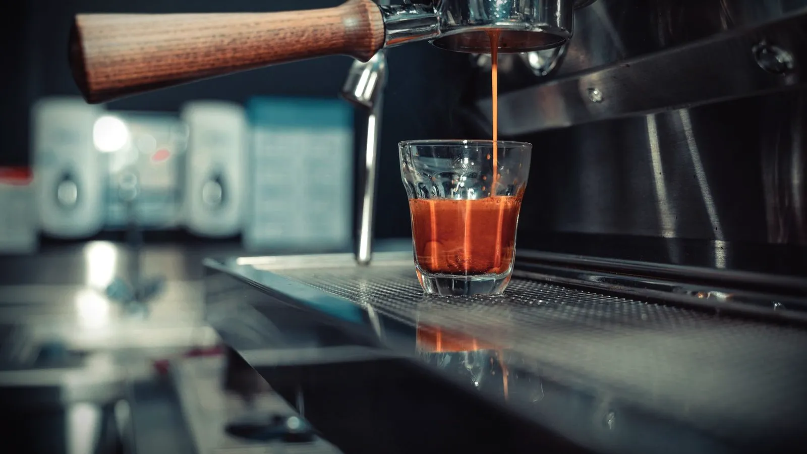 An espresso shot flowing from a portafilter into a small glass