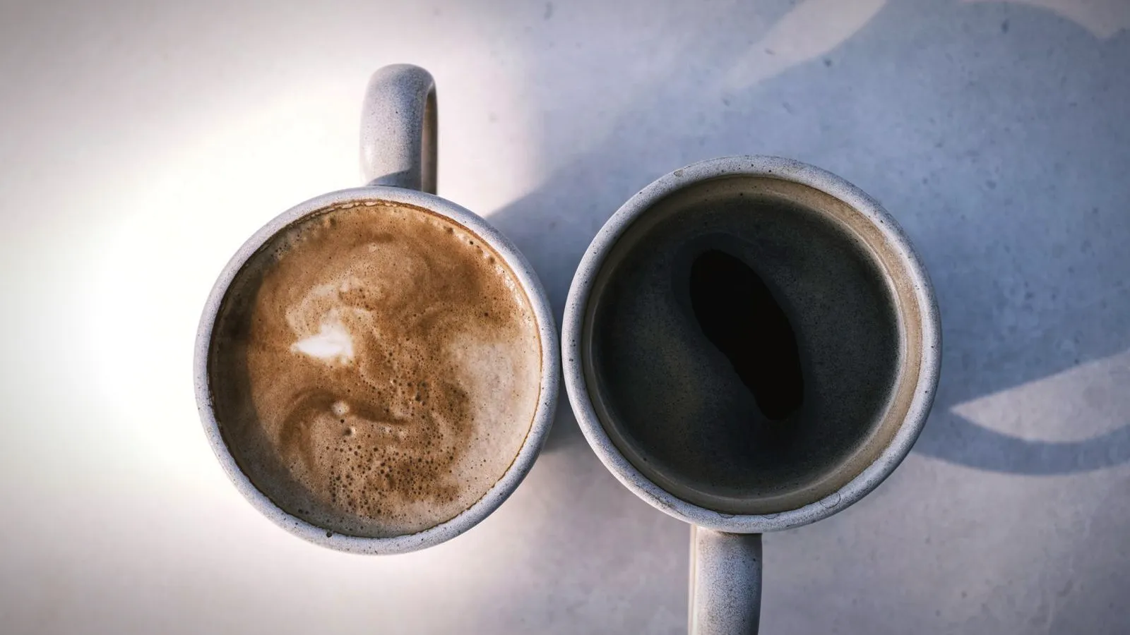 A milky espresso drink beside a cup of black filter coffee, seen from above
