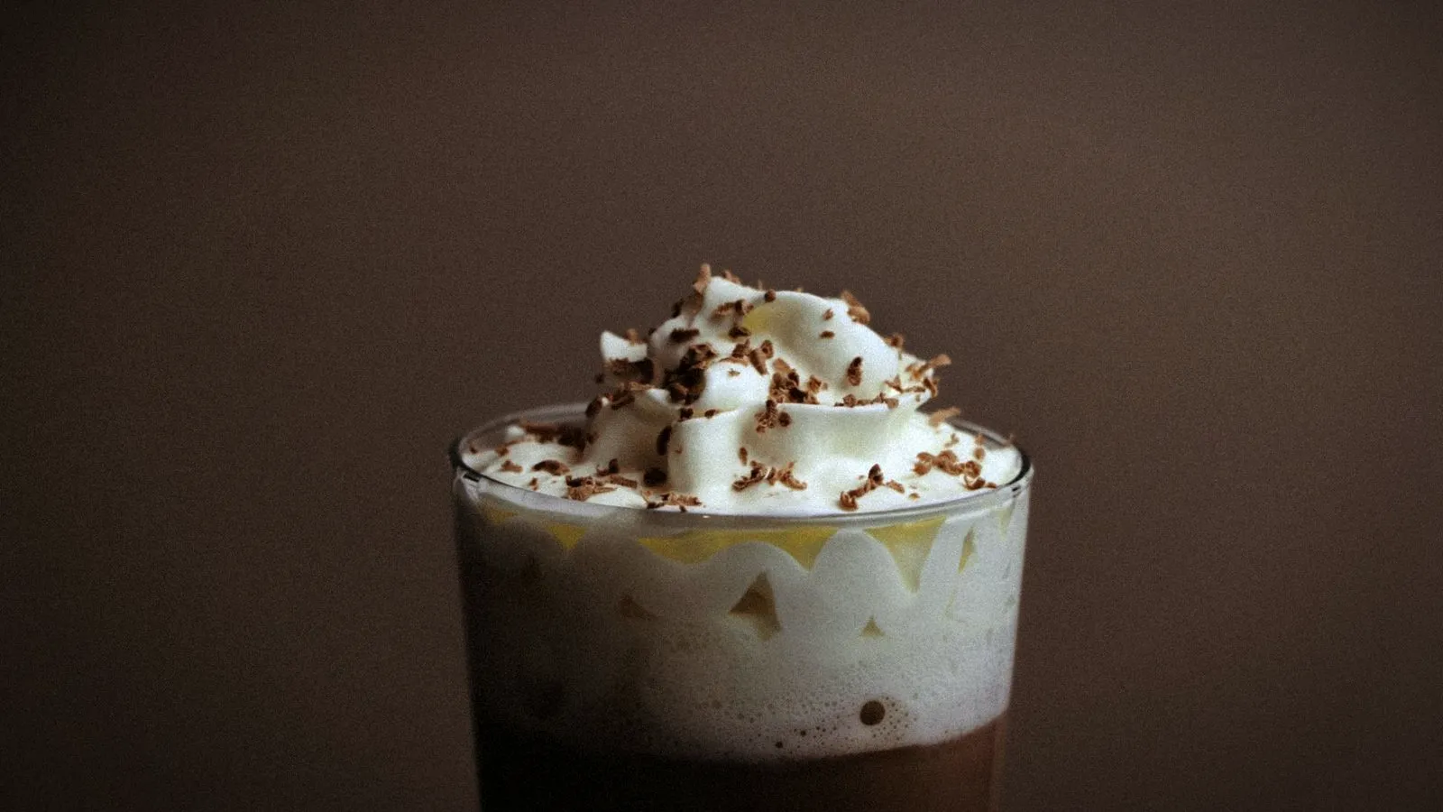 Glass of coffee topped with whipped cream and chocolate shavings
