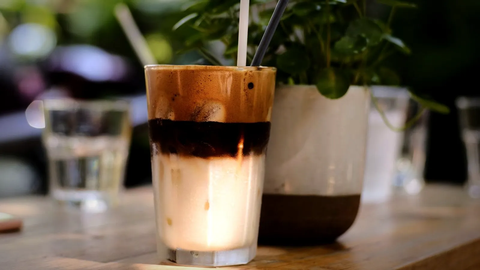 Iced coffee in a tall glass with a dark espresso layer floating over cold milk and ice