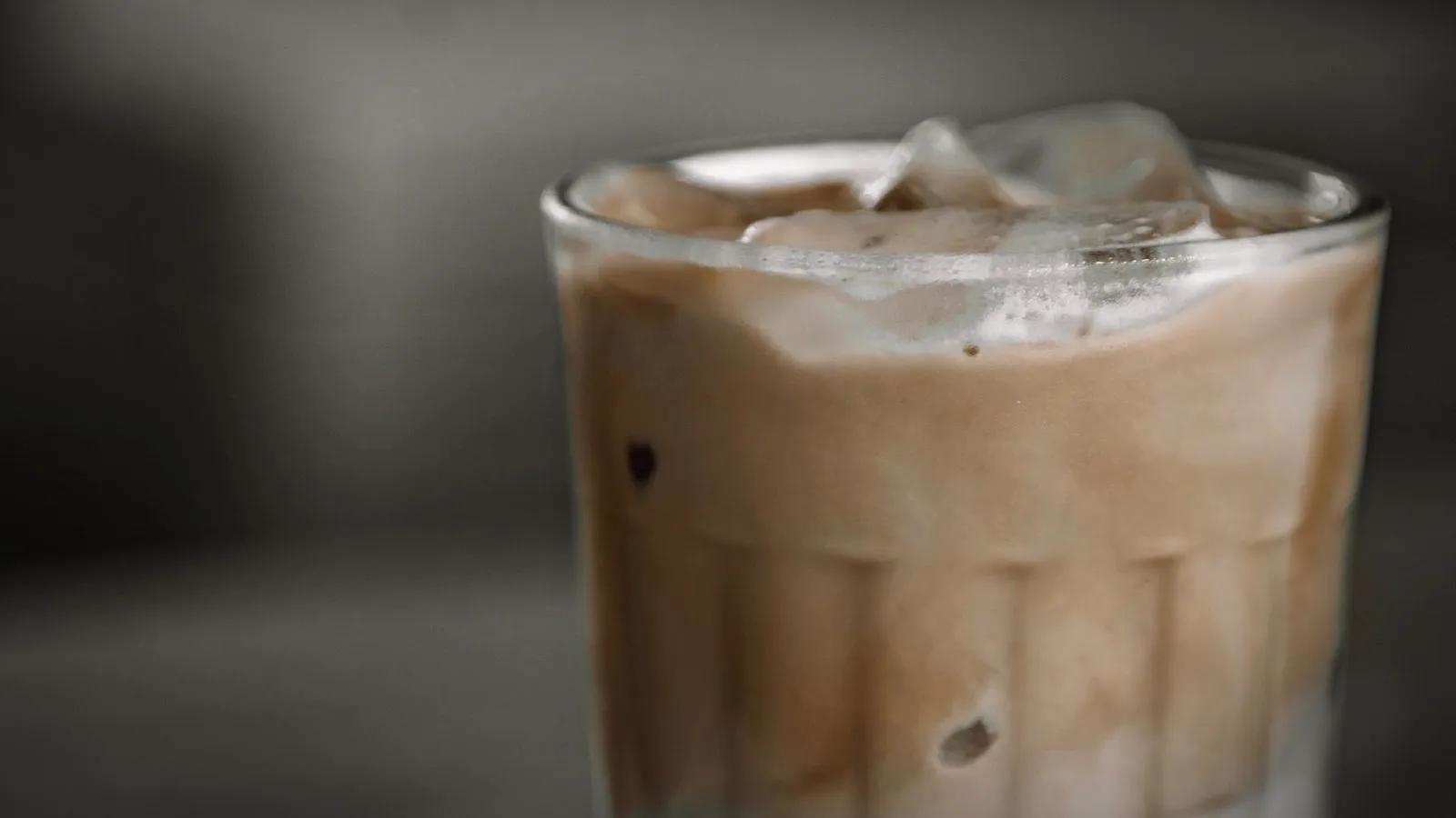 Close-up of an iced latte in a glass with ice cubes and a creamy layer of milk and espresso