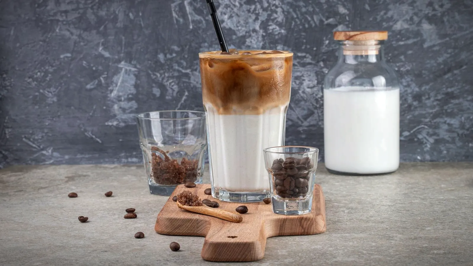 An iced latte with a straw in a tall glass next to a glass bottle of milk