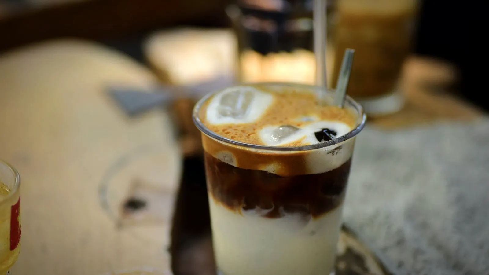 An iced coffee in a glass with a pale milky layer at the bottom and espresso floating above it, topped with ice