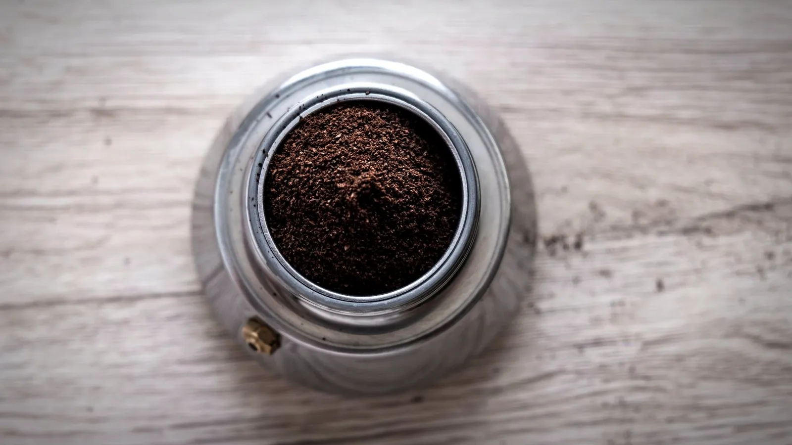 A moka pot filter basket filled with ground coffee