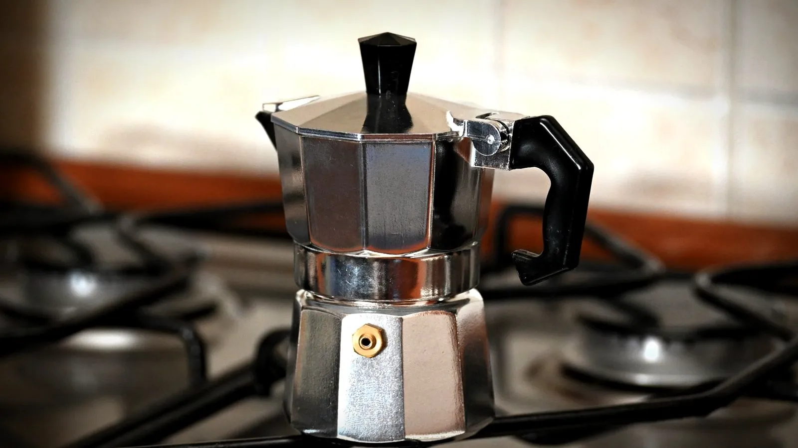 An aluminum stovetop moka pot on a gas burner