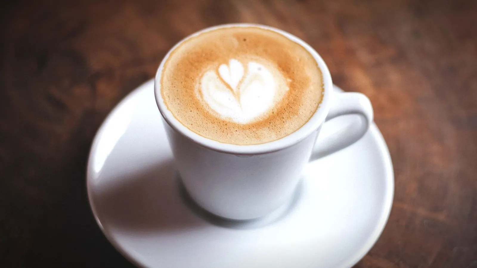 Small white cup of espresso marked with a little milk foam in a tulip shape, on a saucer