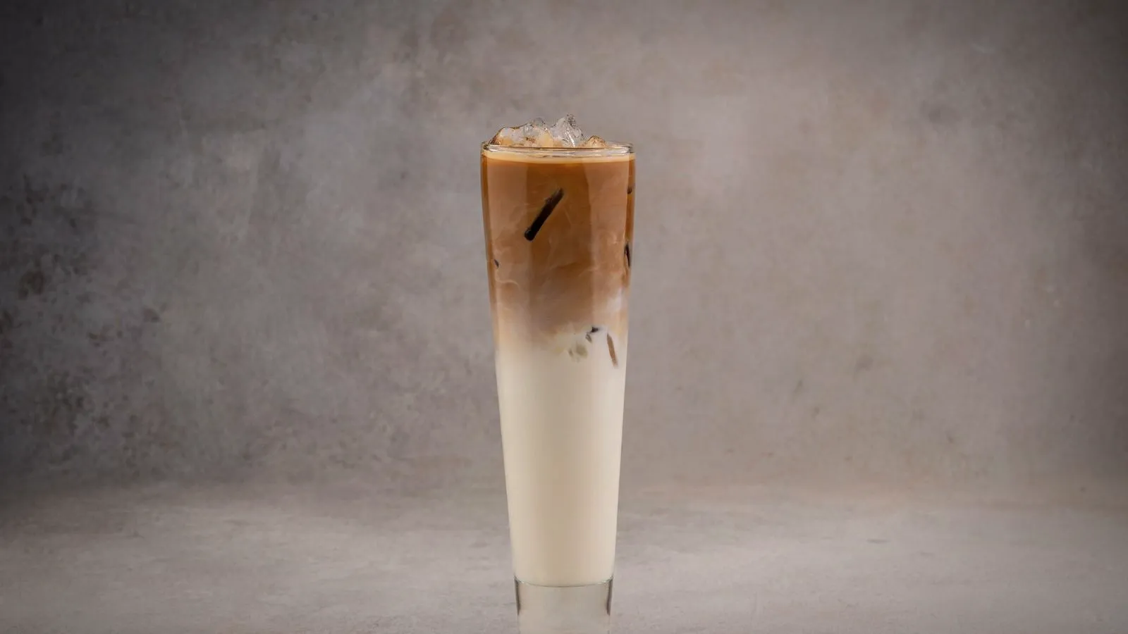 A tall iced latte in a slim glass with espresso settling over cold milk