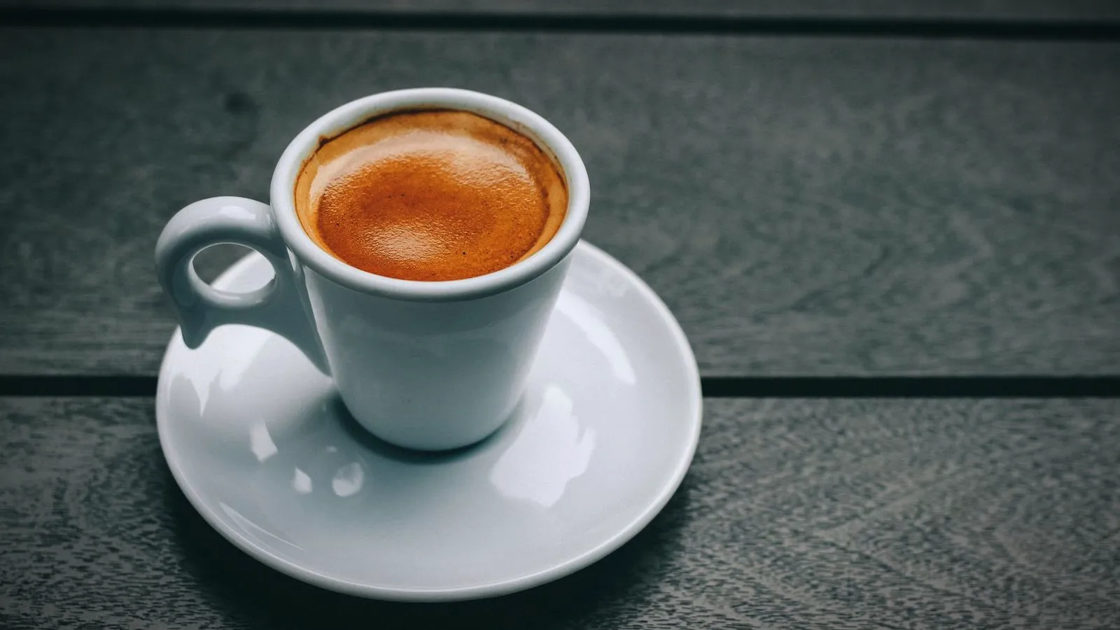 An espresso with crema in a thick-walled white ceramic cup on a saucer
